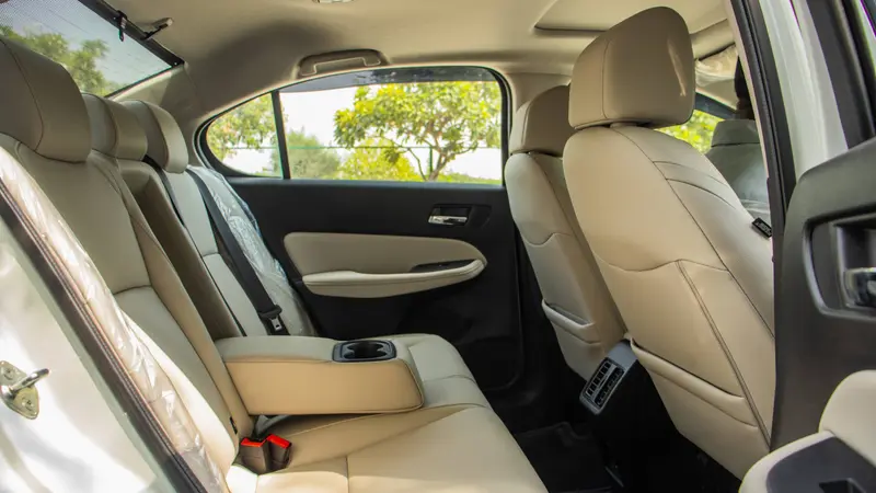 Rear cabin showing beige seats, centre armrest with cupholder and rear AC vents