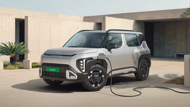 Kia Syros EV charging at an EV charging station, with charging cable attached.