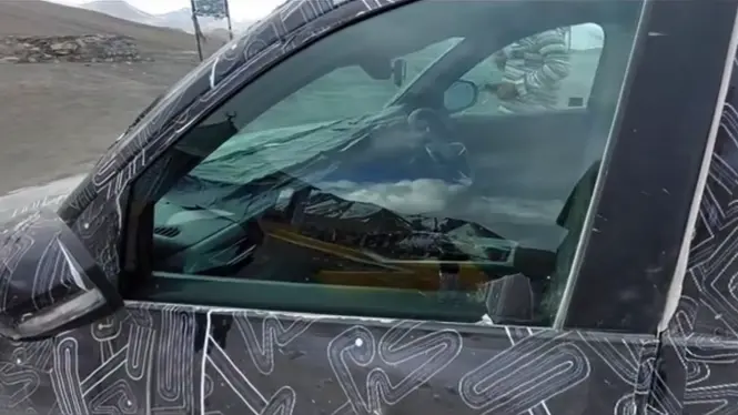 Side view of the camouflaged Renault SUV showing its front door, window line and partially visible interior.