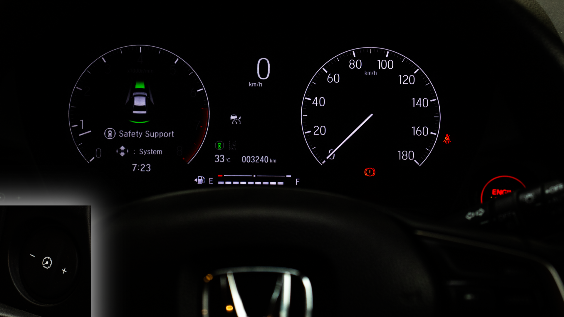 Honda Amaze's Illuminated instrument panel featuring a digital display on the left indicating safety support systems, a traditional analog speedometer on the right, and the top of a Honda steering wheel at the bottom