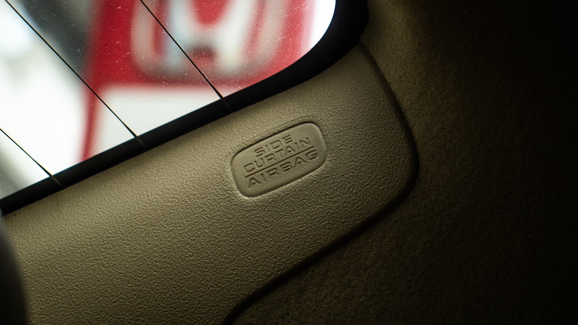Close-up of a beige Honda Amaze interior pillar featuring embossed "SIDE CURTAIN AIRBAG" text
